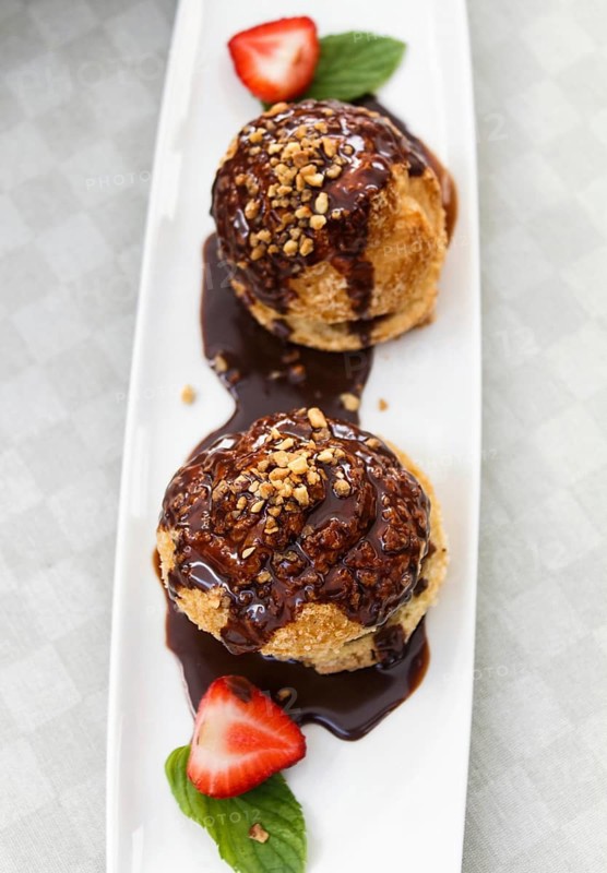Fresh profiteroles with ice cream and chocolate on a white plate. selective focus. horizontal. top view
