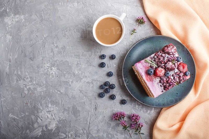 Berry cake with milk cream and blueberry jam on blue ceramic plate with cup of coffee and fresh blueberries on a gray concrete background with orange textile. top view, flat lay, copy space
