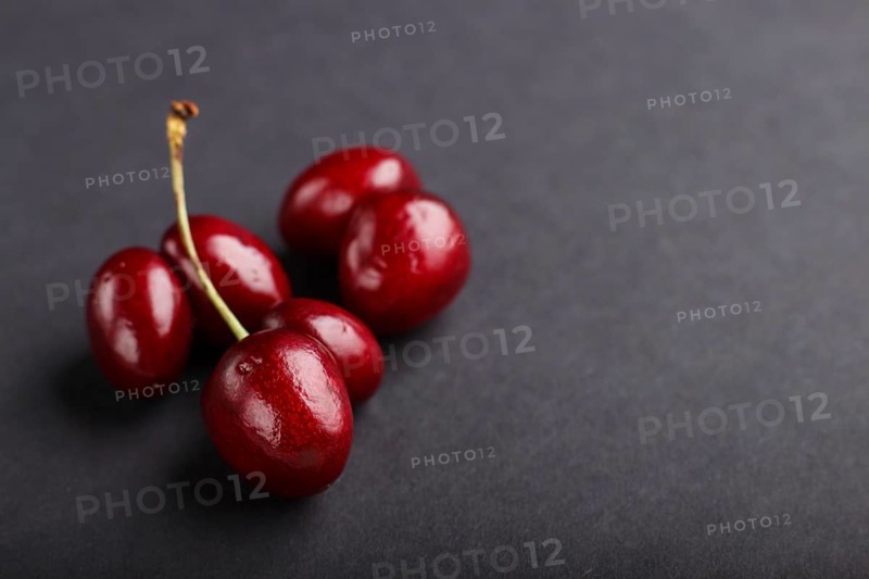 Ugly weird red sweet cherry on black background. side view, close up, copy space, macro, trendy