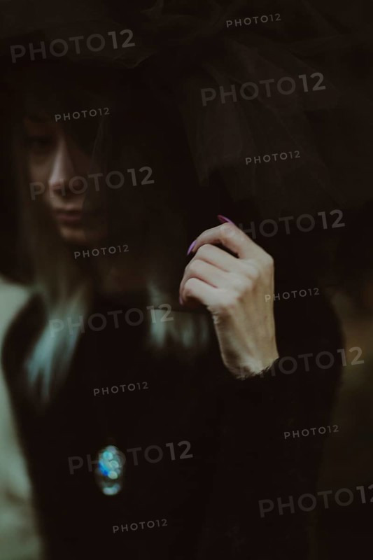 Close-up image with a woman's face partially obscured by tulle fabric, creating an enigmatic feel