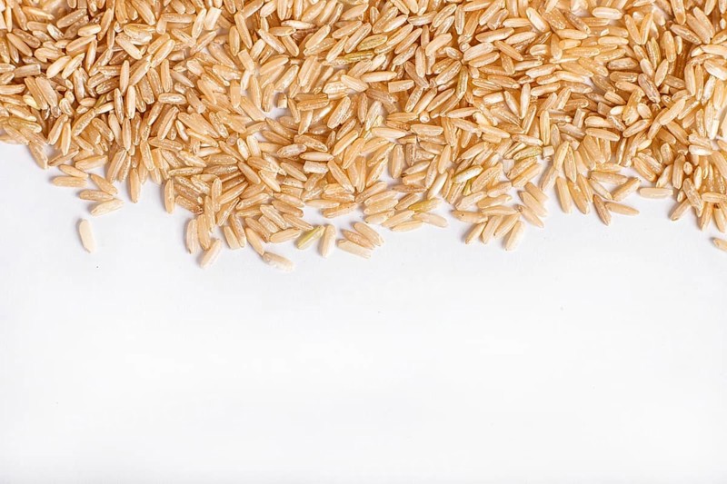 Texture of brown rice isolated on white background. Top view. Copy space