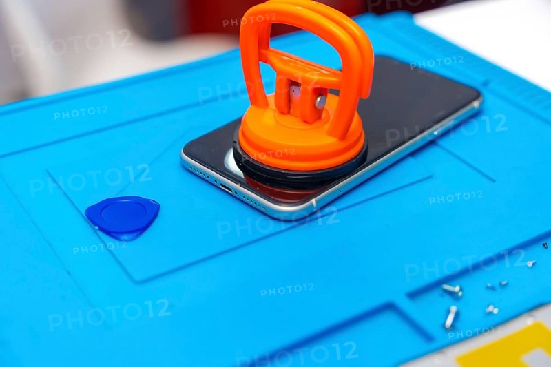 Close-up photo of a suction cup pressing the screen of a mobile to attach it in the desk of a workshop