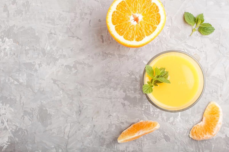 Glass of orange juice on a gray concrete background. Morninig, spring, healthy drink concept. Top view, copy space, flat lay