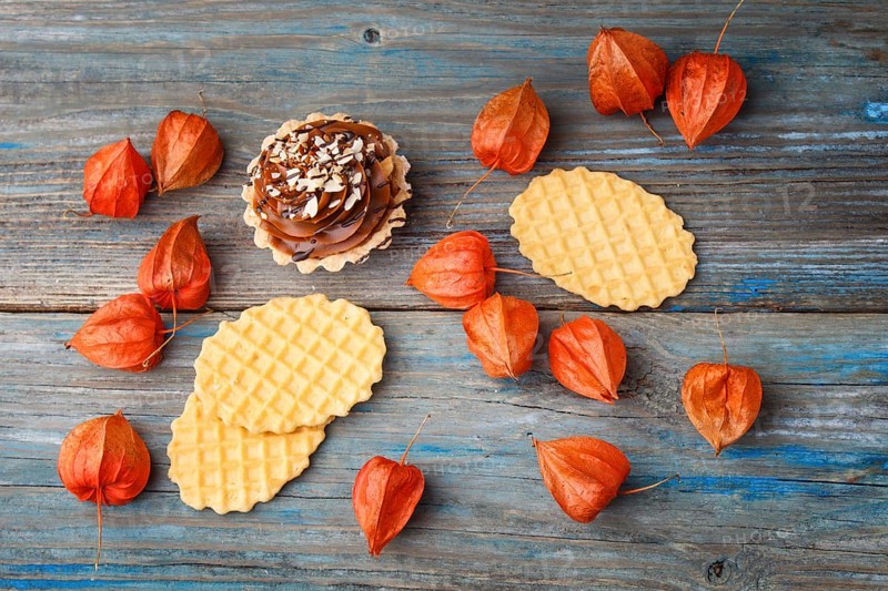 Sweet waffle, cake with cream and red physalis on a rustic blue wooden background