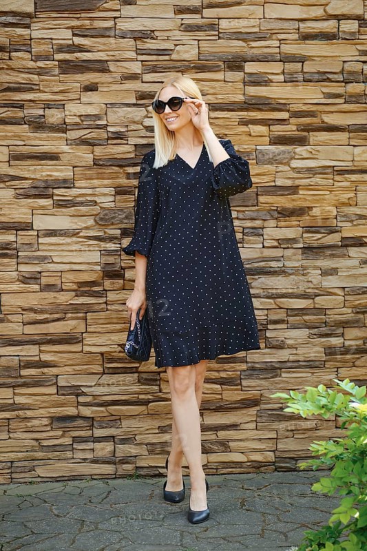 Trendy fashionable businesswoman in loose black dress and sunglasses walking outdoor