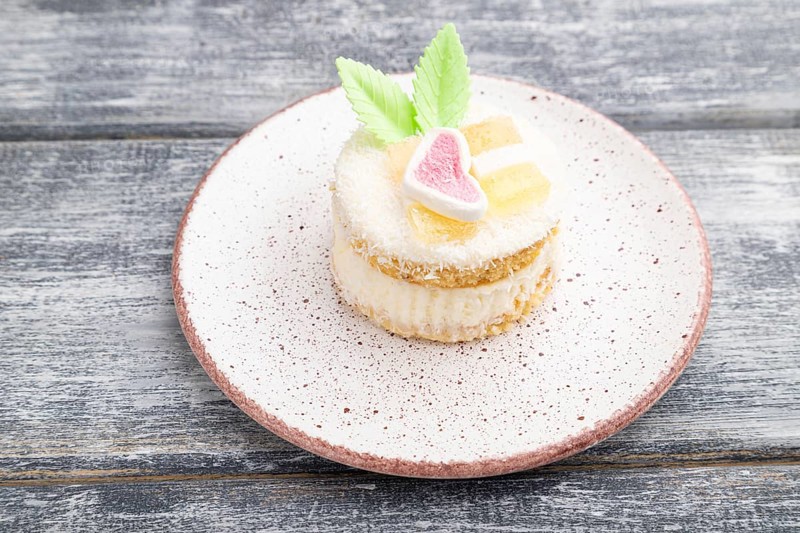 Decorated cake with milk and coconut cream on a gray wooden background. Side view, close up