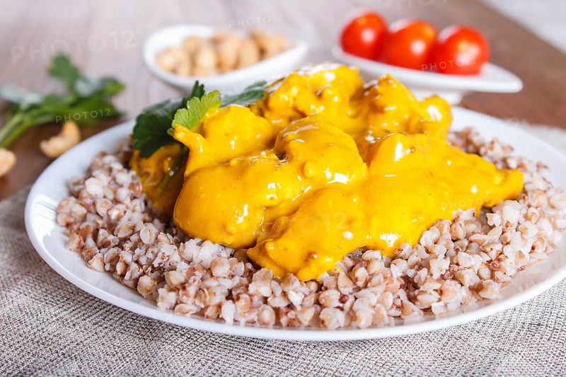 Buckwheat with chicken curry sauce with cashew on brown wooden background. close up, selective focus