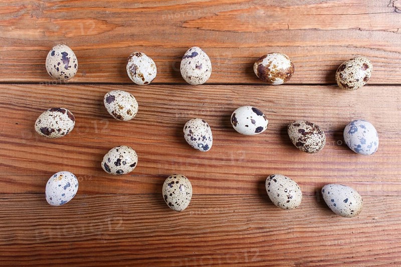 Raw quail eggs on a brown wooden background. top view