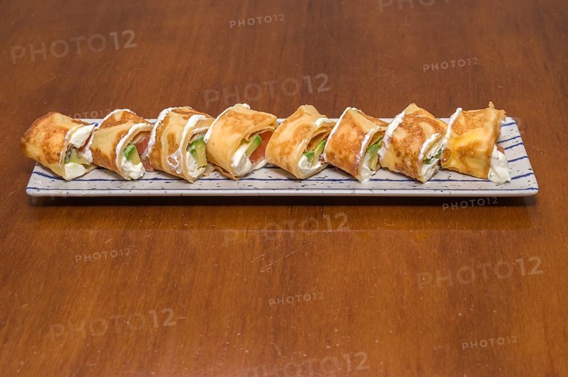 A plate of sushi rolls topped with cream sauce and slices of green lettuce, Majorca, Balearic Islands, Spain, Europe