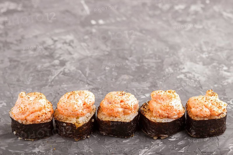 Japanese maki sushi rolls with flying fish roe, cheese on black concrete background. Side view, close up, copy space