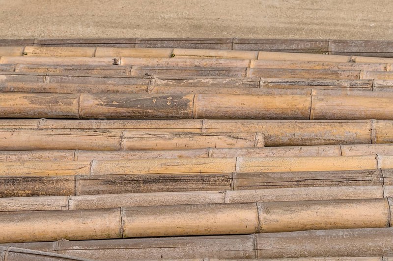 Closeup of weathered cracked bamboo poles laying on concrete in South Korea