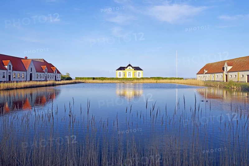 Large houses and the teahouse at Valdemars Slot are reflected in the calm water, Valdemars Slot, Manor Route, Tasinge, Denmark, Europe