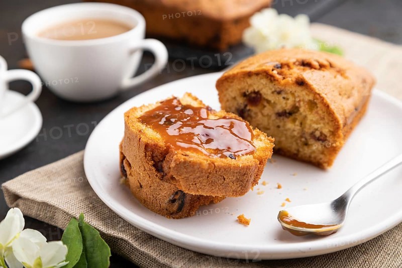 Homemade cake with raisins, almonds, soft caramel and a cup of coffee on a black concrete background and linen textile. Side view, close up, selective focus