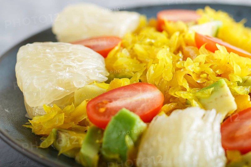 Fried pomelo with tomatoes and avocado on gray concrete background. side view, close up, selective focus, myanmar food