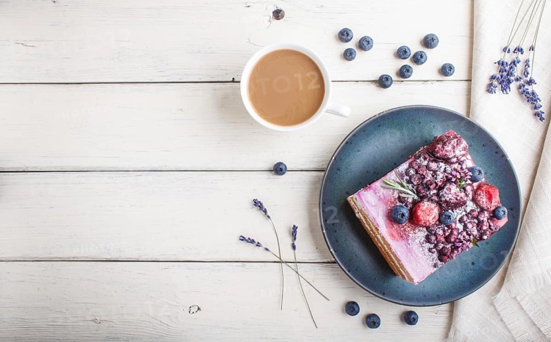Berry cake with milk cream and blueberry jam on blue ceramic plate with cup of coffee and fresh blueberries on a white wooden background. top view, flat lay, copy space