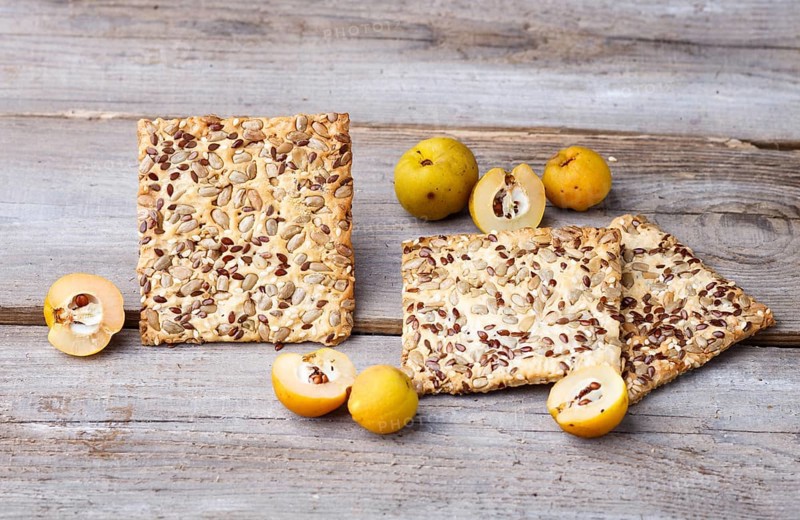 Biscuits with flax, sesame and sunflower seeds and yellow quince fruit on a rustic wooden background