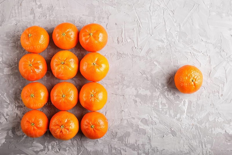 Rows of tangerines forming a rectangle and one tangerine on a gray concrete background, top view, flat lay