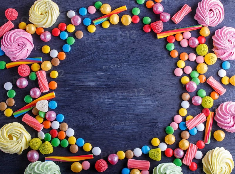 Colorful frame of multicolored candies on black wooden background. Circle copy space, top view, flat lay
