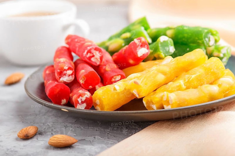 Set of various traditional turkish delight (rahat lokum) in blue ceramic plate with cup of coffee on a gray concrete background. side view, close up, selective focus