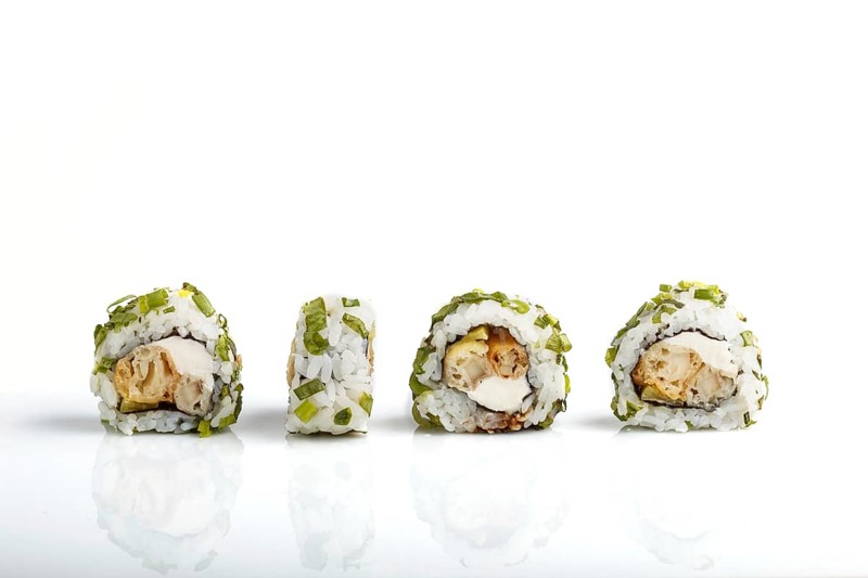 Four Japanese maki sushi rolls in a row with cream cheese and onion isolated on white background.Side view, close up