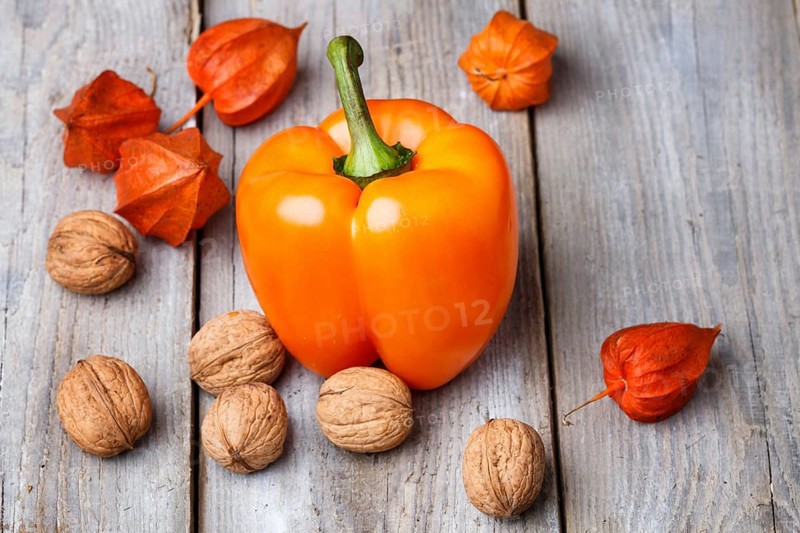 Walnuts, orange pepper and red physalis on rustic wooden background with copy space