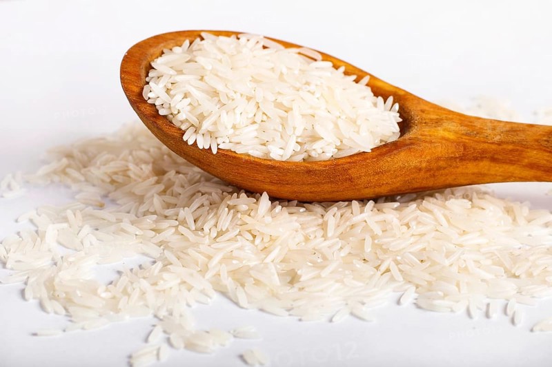 Pile of basmati rice in a wooden spoon isolated on white background