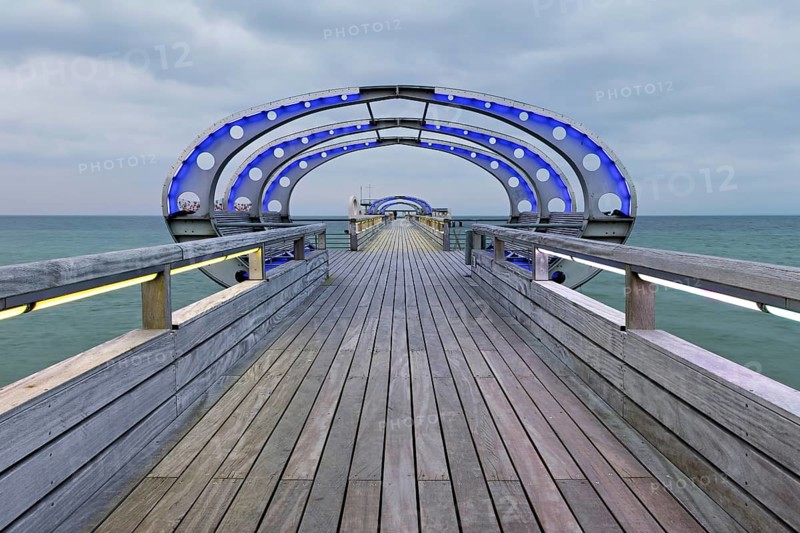 Long exposure of the Kellenhusen pier on the Baltic Sea with blue illuminated arcades