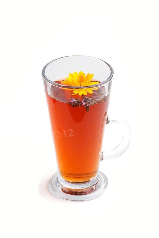 Glass of herbal tea with calendula and hyssop isolated on white background. Morninig, spring, healthy drink concept. Side view, close up