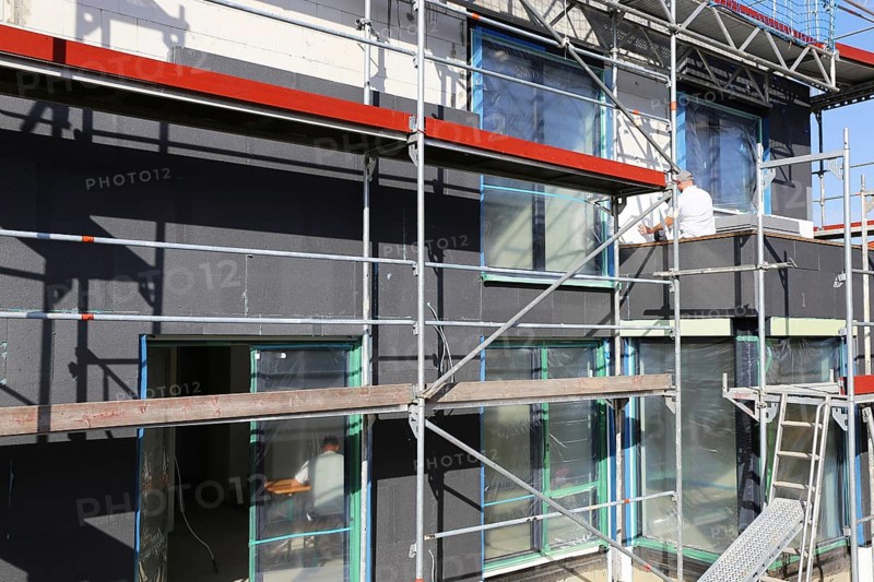 Construction workers insulate a house facade