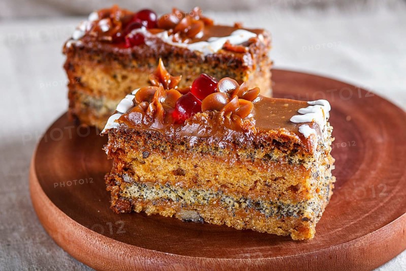 A piece of cake with caramel cream and poppy seeds on a wooden kitchen board. close up, selective focus, white background