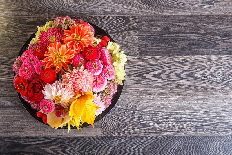 Floral arrangement of autumn flowers on a plate. dahlia, zinnia, rose, orchid, maple leaves. copy space