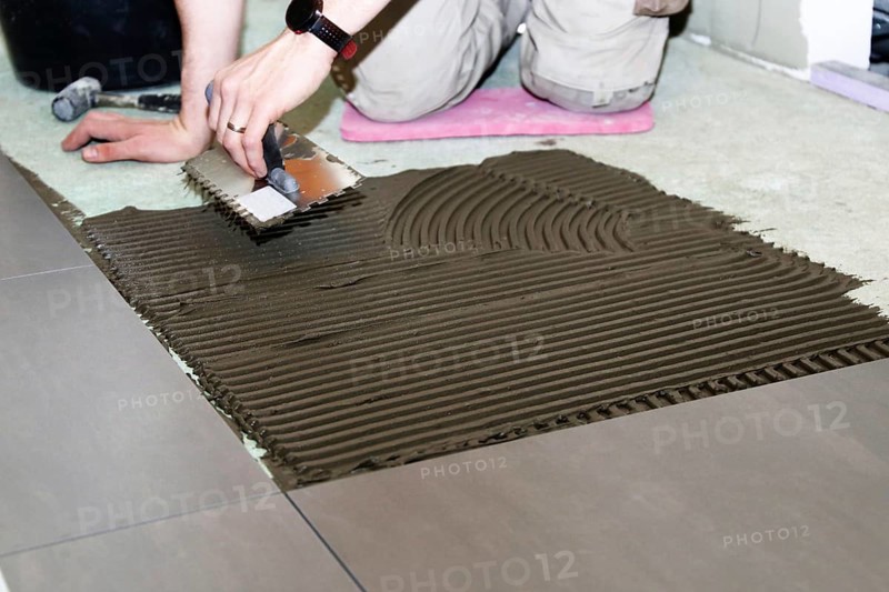 Tiler lays modern large floor tiles in a bathroom