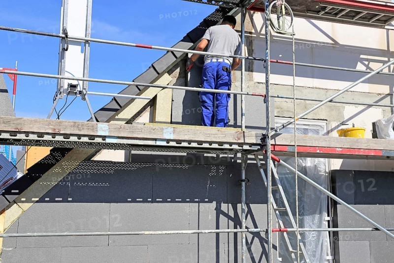 Construction workers insulate a house facade