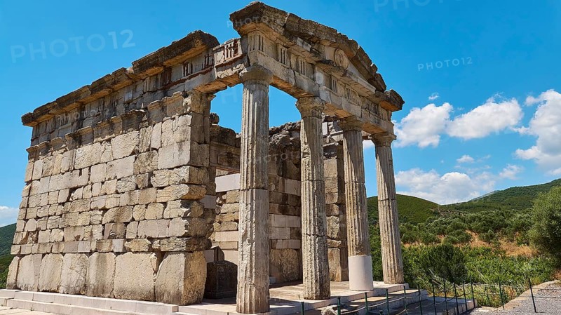 Ancient columned building in front of a blue sky with decorative clouds, Mausoleum, Heroon, Archaeological site, Ancient Messene, Capital of Messinia, Messini, Peloponnese, Greece, Europe