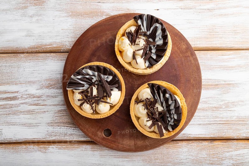 Sweet tartlets with chocolate and cheese cream on a white wooden background. top view, flat lay, copy space.close up
