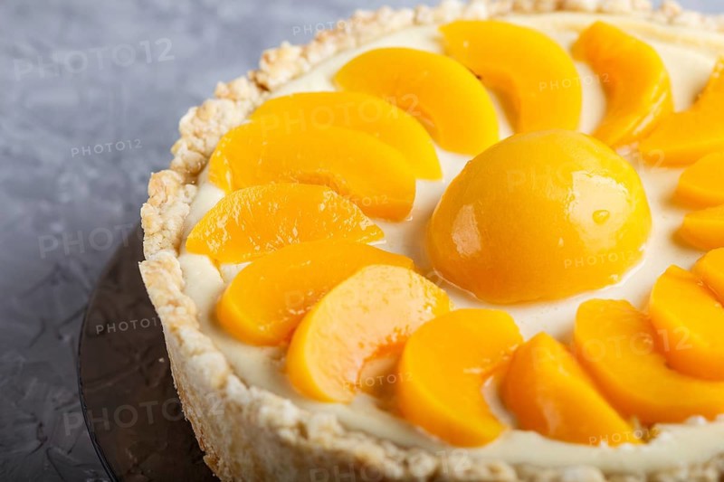 Round peach cheesecake on a gray concrete background. side view, close up