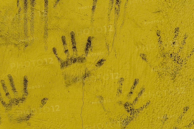 Black hand prints on side of cracked yellow wall in South Korea