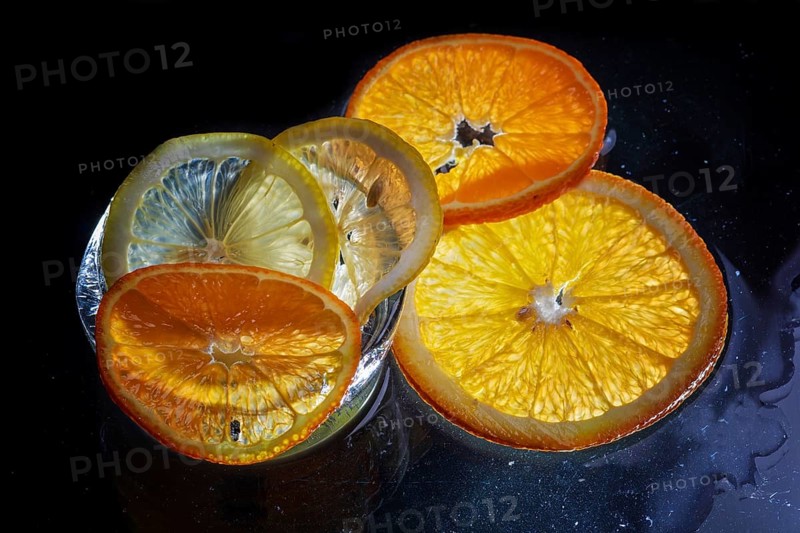 Transparent slices of fresh oranges and lemons on the glass with ice
