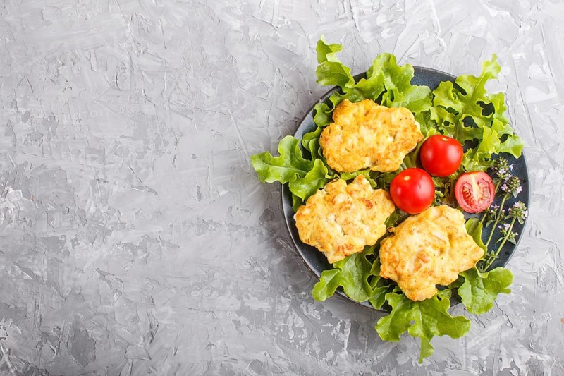Minced chicken cutlets with lettuce, tomatoes and herbs on a gray concrete background. top view, flat lay, copy space