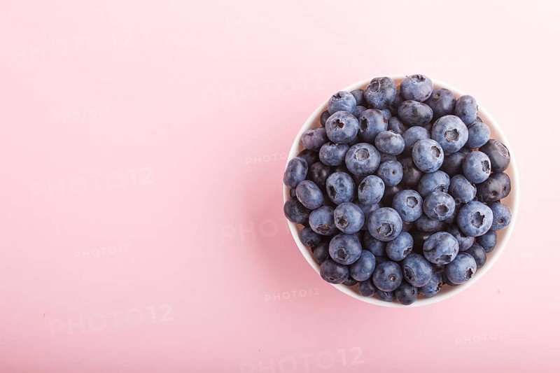 Fresh blueberry in white bowl on pink background. top view, copy space, flat lay