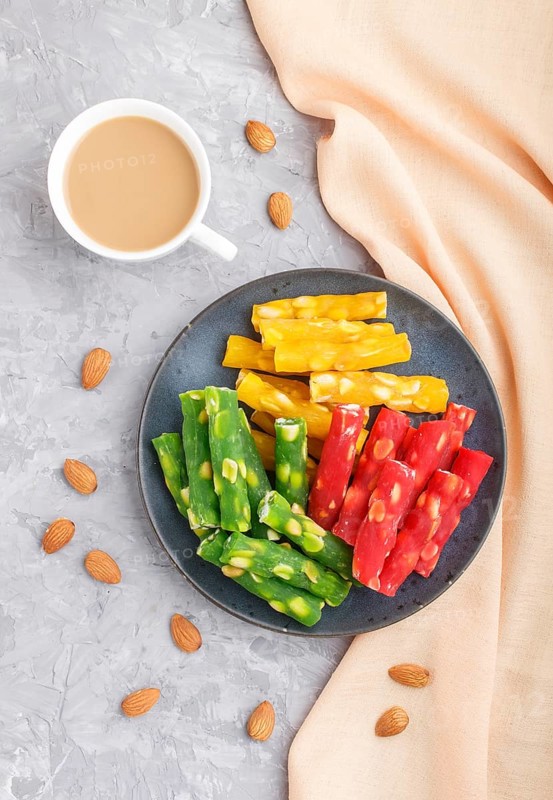 Set of various traditional turkish delight (rahat lokum) in blue ceramic plate with cup of coffee on a gray concrete background. top view, flat lay
