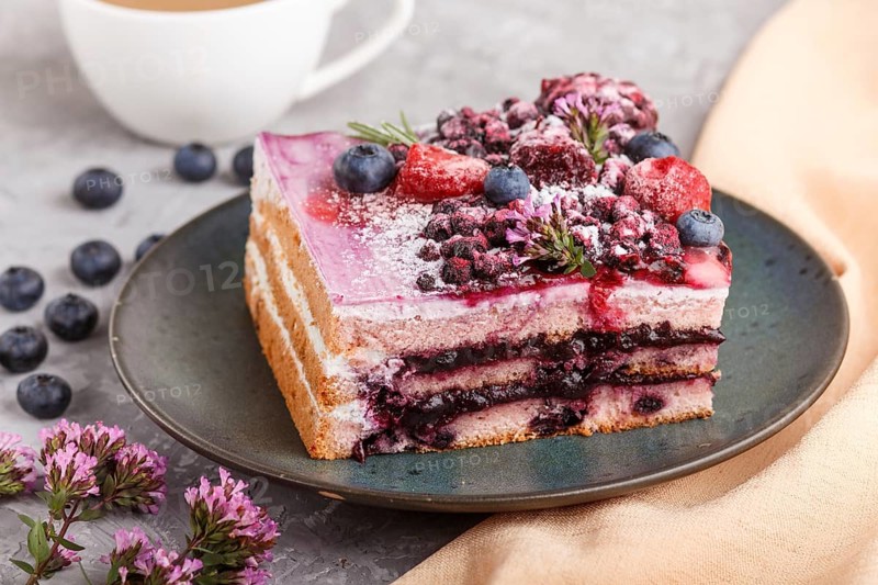 Berry cake with milk cream and blueberry jam on blue ceramic plate with cup of coffee and fresh blueberries on a gray concrete background with orange textile. side view, close up, selective focus