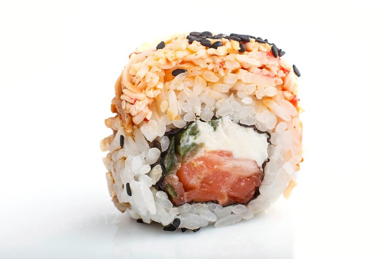 Japanese maki sushi rolls with salmon, sesame, isolated on white background. Side view, close up, selective focus