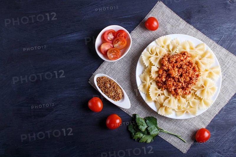 Farfalle bolognese pasta with minced meat on black wooden background. top view, copy space