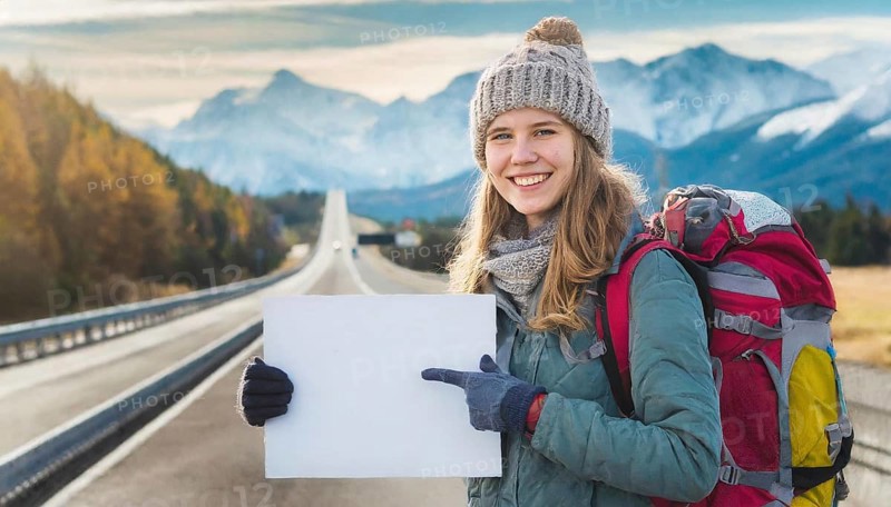 AI generated, human, humans, person, persons, woman, woman, one person, 20, 25, years, outdoor shot, seasons, cap, bobble hat, gloves, winter jacket, cold, cold, backpack, woman wants to travel, hitchhiking, hitchhiking, hitchhiking, road, motorway, holding a white sign, text free space