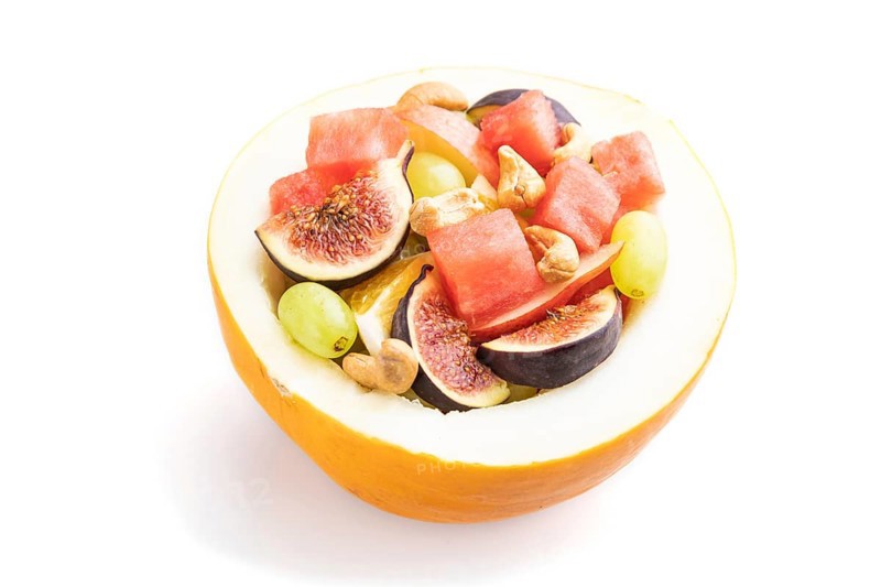 Vegetarian fruit salad of watermelon, grapes, figs, pear, orange, cashew isolated on white background. Side view, close up