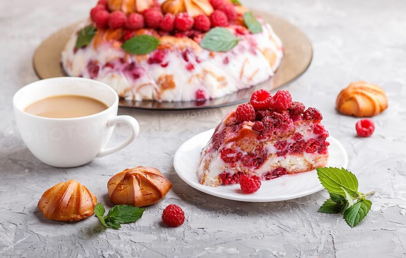 Homemade jelly cake with milk, cookies and raspberry on a gray concrete background with cup of coffee. side view. close up