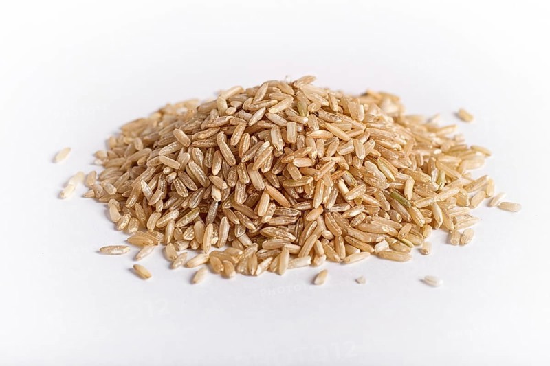 Pile of brown rice isolated on white background. Closeup