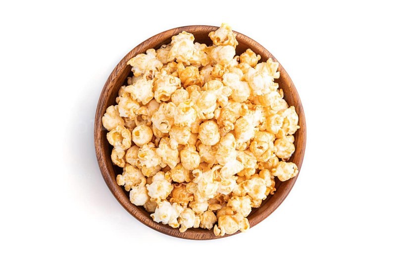 Popcorn with caramel in wooden bowl isolated on white background. Top view, flat lay, close up