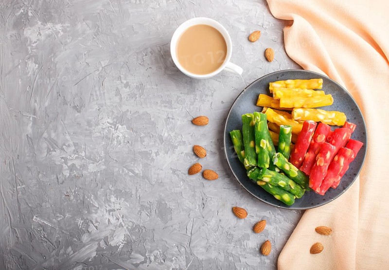 Set of various traditional turkish delight (rahat lokum) in blue ceramic plate with cup of coffee on a gray concrete background. top view, flat lay, copy space